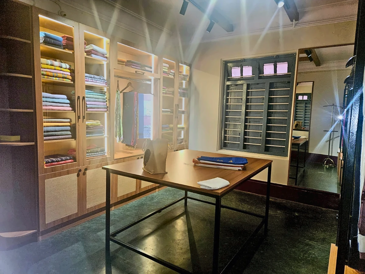 Wide view of the Sutra Kalaa selection room with illuminated saree cabinets and a central selection table